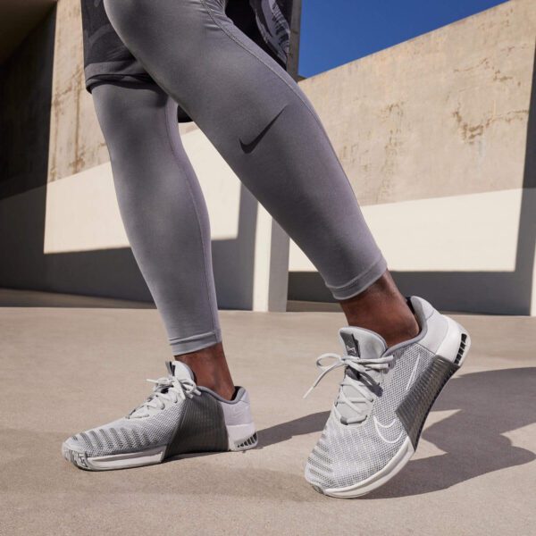 کفش کراسفیت اورجینال برند Nike مدل Metcon 9 با رنگ خاکستری روشن داخل پای مدل در حال تمرین از نمای نزدیک