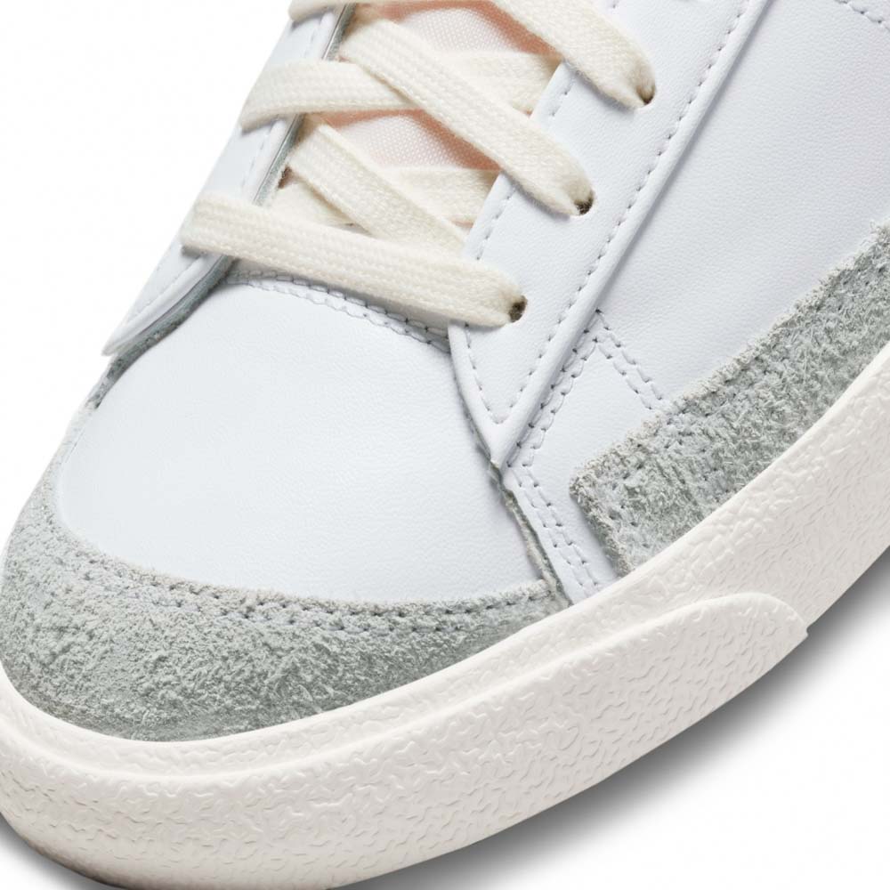 کتونی اورجینال برند Nike مدل Blazer Low 77 رنگ سفی با جزئیات آبی و طوسی از نمای زبانه