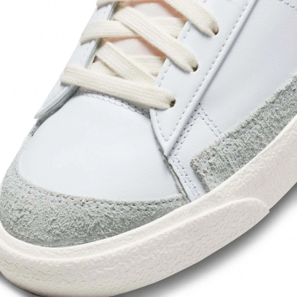 کتونی اورجینال برند Nike مدل Blazer Low 77 رنگ سفی با جزئیات آبی و طوسی از نمای زبانه