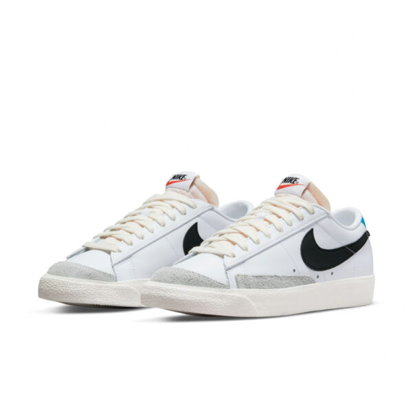 کتونی اورجینال برند Nike مدل Blazer Low 77 رنگ سفید با جزئیات آبی و طوسی نمای جهت دار از بغل