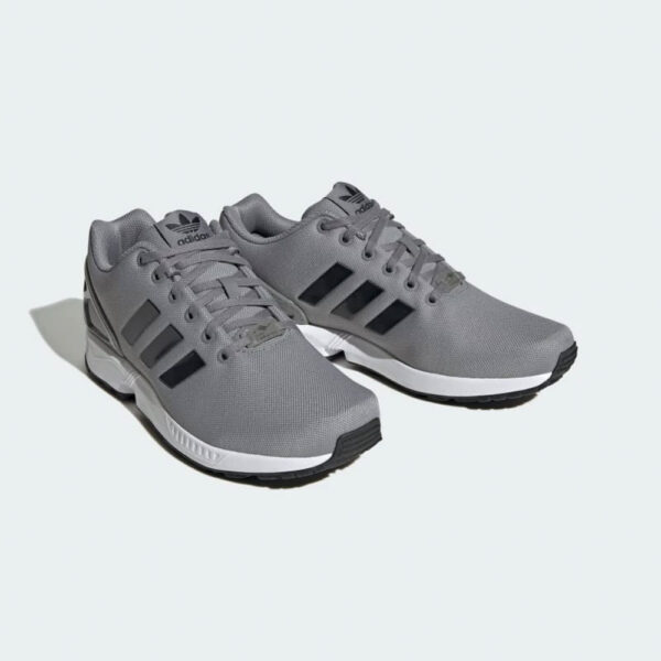کتونی اورجینال برند Adidas مدل Flux رنگ خاکستری با جزئیات مشکی نمای جهت دار از جلو